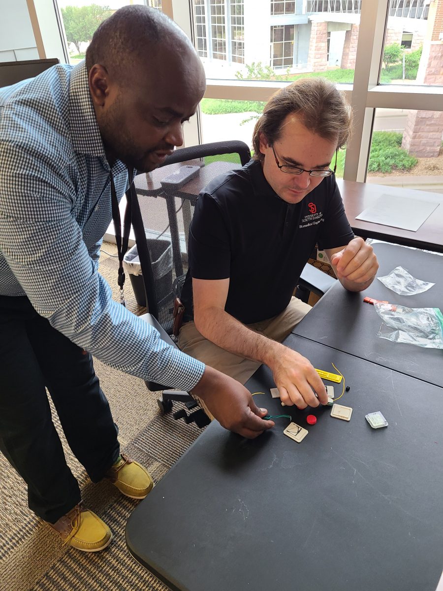 Etienne Gnimpieba and Tim Hartman examine structures they've 3D-printed.