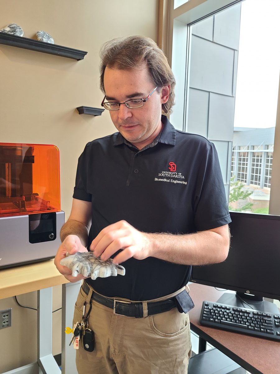 Tim Hartman examines a large-scale 3D print of a human cell.